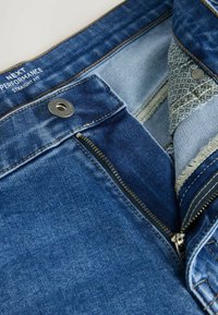 Jeans in denim a vestibilità dritta con zip, colore blu scuro, hardware in rame e una cintura interna testurizzata con bordi in tessuto stampato.