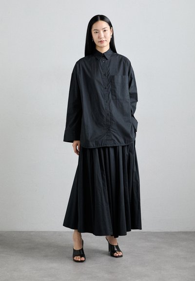 Black button-up shirt with a pocket, paired with a pleated black skirt. The outfit features a clean, minimalist design with soft fabric.