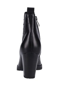 Botas negras de cuero hasta el tobillo con un alto tacón apilado, cremallera lateral, panel elástico y detalles de tachuelas a lo largo del eje. Suela texturizada.