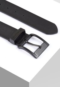 Zwarte leren riem met een gladde textuur, een rechthoekige zwarte metalen gesp en vijf verstelgaten langs de band.