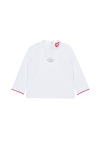 Camicia bianca a maniche lunghe con scollatura rotonda, presenta orli rosa a scallop e un piccolo logo grigio sulla parte anteriore. Etichetta visibile al colletto.