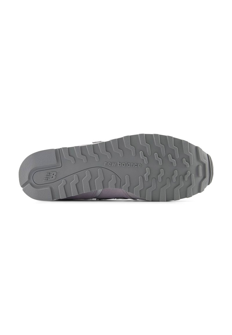 Suela de zapatilla gris con surcos profundos y texturizados para tracción. Presenta el logo "New Balance" grabado cerca del talón. Diseño de punta redondeada.