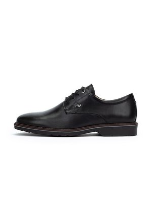 Zapato de vestir de cuero negro con textura suave, punta redondeada y cinco ojetes. Presenta un logo sutil y una suela de goma de perfil bajo.