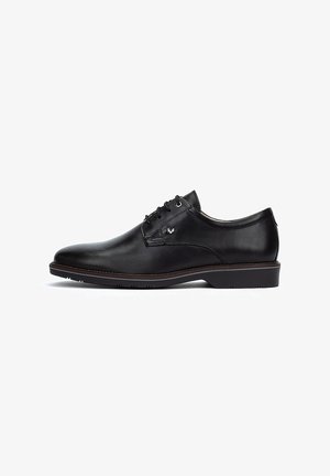Zapato de vestir de cuero negro con textura suave, punta redondeada y cinco ojetes. Presenta un logo sutil y una suela de goma de perfil bajo.