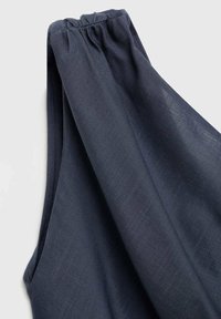 Top fără mâneci de culoare albastru marin, cu un guler plisat, realizat dintr-un material texturat. Prezintă un design relaxat, fluid, cu falduri moi.