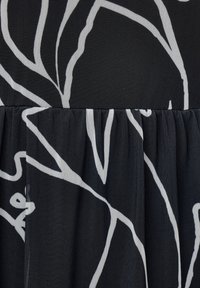 Černá látka s bílým abstraktním liniovým vzorem, nabízející texturovaný povrch a skládání na spodní části.