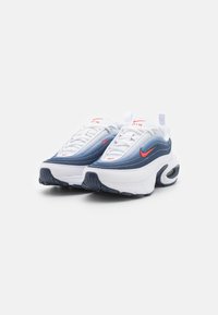 Le sneakers Nike Air Max presentano una combinazione di colori bianco, blu e rosso, materiale sintetico liscio, forma arrotondata e ammortizzazione ad aria visibile nella suola.