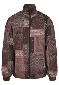 Veste coupe-vent dans des tons de bordeaux et marron, présentant un design patchwork avec des motifs cachemire et des poignets élastiques. Fermeture à glissière à l'avant.