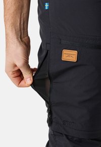 Black outdoor pants with a zippered pocket, featuring a tan label with the text "SWEDEMOUNT" and a small Swedish flag attached.