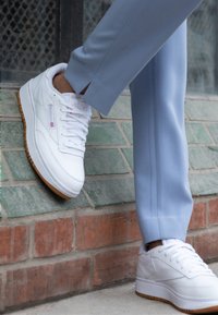 Vita lädersneakers med en slät yta, med en gummisula och subtila varumärkesdetaljer. Bärs tillsammans med ljusblå skräddarsydda byxor.