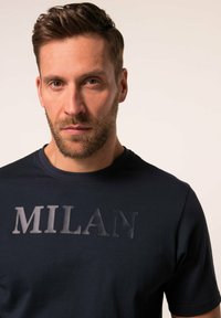 Námořnická modrá trička s kulatým výstřihem vyrobená z bavlny s texturovaným potiskem "MILAN" v světlejším odstínu na přední straně. Krátké rukávy, minimalistický design.