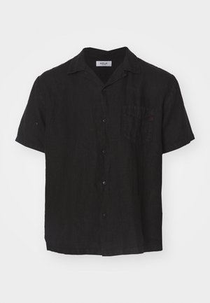 Chemise noire à manches courtes en tissu texturé. Elle présente un devant à boutons, un col et une poche plaquée sur la poitrine gauche.