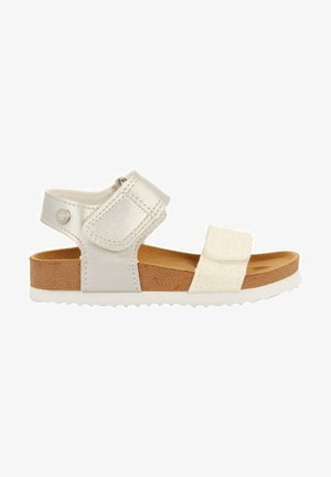 Meisjessandalen met een zilveren synthetisch bovenwerk, klittenbandsluitingen, witte accenten, een kurken voetbed en een gestructureerde rubberen zool.