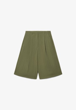 Pantaloncini corti a gamba larga in verde oliva con cucitura frontale, tasche laterali, passanti per cintura e chiusura frontale con zip nascosta.