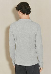 Langærmet skjorte i meleret grå stof, med rund halsudskæring og en tekstureret overflade. Slim fit med tætsiddende ærmer og kant.