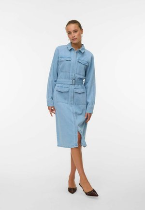 Robe chemise en denim bleu avec des manches longues, un col, deux poches poitrine, une fente sur le côté et une ceinture assortie. Présente une texture douce et un design structuré.
