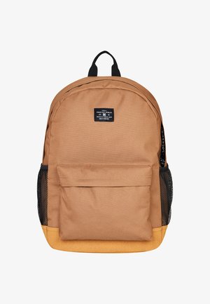 Brązowy plecak z tkaniny z czarnymi akcentami, z przednią kieszenią, siateczkowymi kieszeniami bocznymi oraz zaokrąglonym dnem. Teksturowany materiał z etykietą.