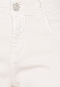 Jean en denim blanc avec fermeture à bouton, poches avant et détails de couture subtils. Texture lisse avec une coupe ajustée.