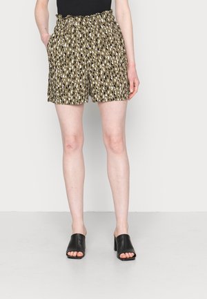 Person trägt hoch taillierte, olivgrüne Shorts mit schwarz-weißem Leopardenmuster, schwarzes ärmelloses Oberteil und schwarze offene, hochhackige Mules.