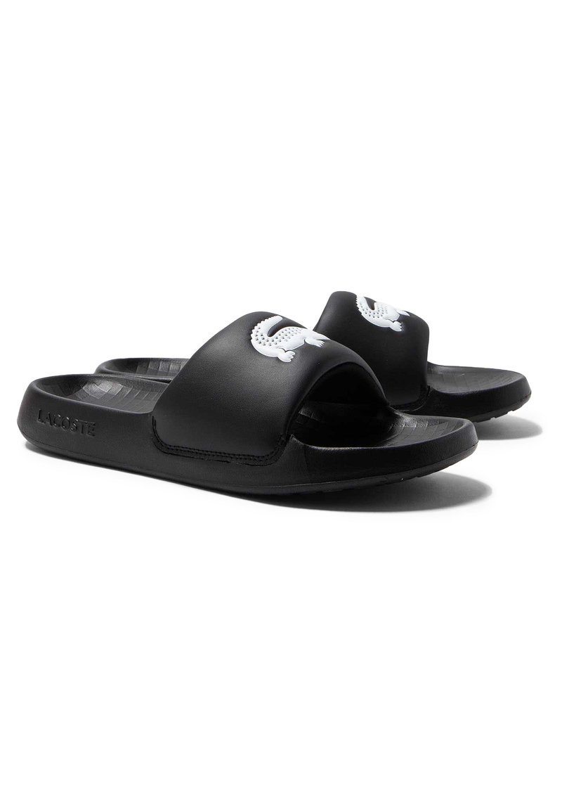 Black rubber slide sandals with a wide strap and a white logo. Textured insole and a flexible sole for comfort.