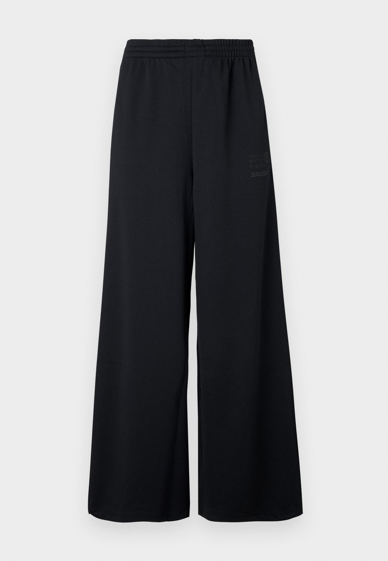 Pantaloni neri a gamba larga realizzati in tessuto a rete testurizzata. Caratterizzati da una vita elasticizzata e una stampa logo sottile sul lato.