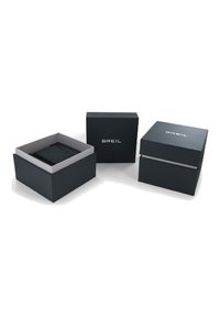 Sorte papkasser med grå indvendige. En boks er åben med et aftageligt låg, som viser en mindre boks ved siden af, begge mærket "BREIL."