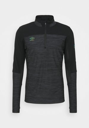 Polo sportif pour homme à manches longues, noir et gris foncé, avec une fermeture éclair quart de longueur et un logo Umbro vert sur la poitrine et la manche.