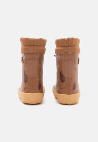 Botas de goma impermeables marrones con un patrón de flores y hojas, puños de tela beige y suelas amarillas texturizadas para un mejor agarre.