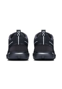 Chaussures de sport noires avec dessus en maille, accents réfléchissants et semelle amortissante. La vue arrière montre des languettes de traction et un design épuré.