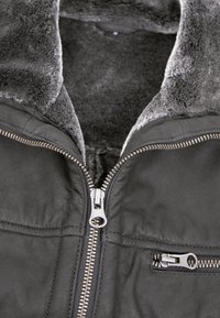 Schwarze Lederjacke mit einem grauen, fleecegefütterten Kragen, ausgestattet mit einem vorderen Reißverschluss und einer zusätzlichen Reißverschlusstasche auf der Brust.
