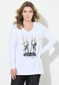 Langärmliges weißes T-Shirt mit einem grafischen Motiv von braunen gemusterten Stiefeln mit schwarzen Fellakzenten und Bändern. Weicher Stoff mit einem V-Ausschnitt.