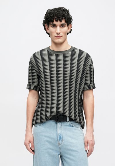 Pull en maille à rayures noir et gris à manches courtes, avec un col côtelé et des manches retroussées, associé à un jean en denim clair.