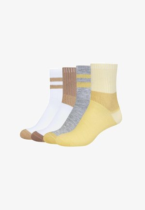 Fire par ribstrikkede ankelstrømper i hvid, brun, grå med gule striber og ensfarvet gul, lagt side om side på en hvid baggrund.