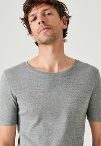 T-shirt grigio a maniche corte realizzato in tessuto morbido. Presenta un collo rotondo e una vestibilità casual con dettagli minimi, adatto per l'uso quotidiano.