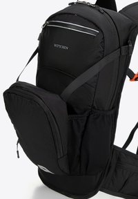 Mochila negra hecha de tejido texturizado que cuenta con correas ajustables acolchadas, un bolsillo frontal con cremallera y detalles de malla para ventilación.