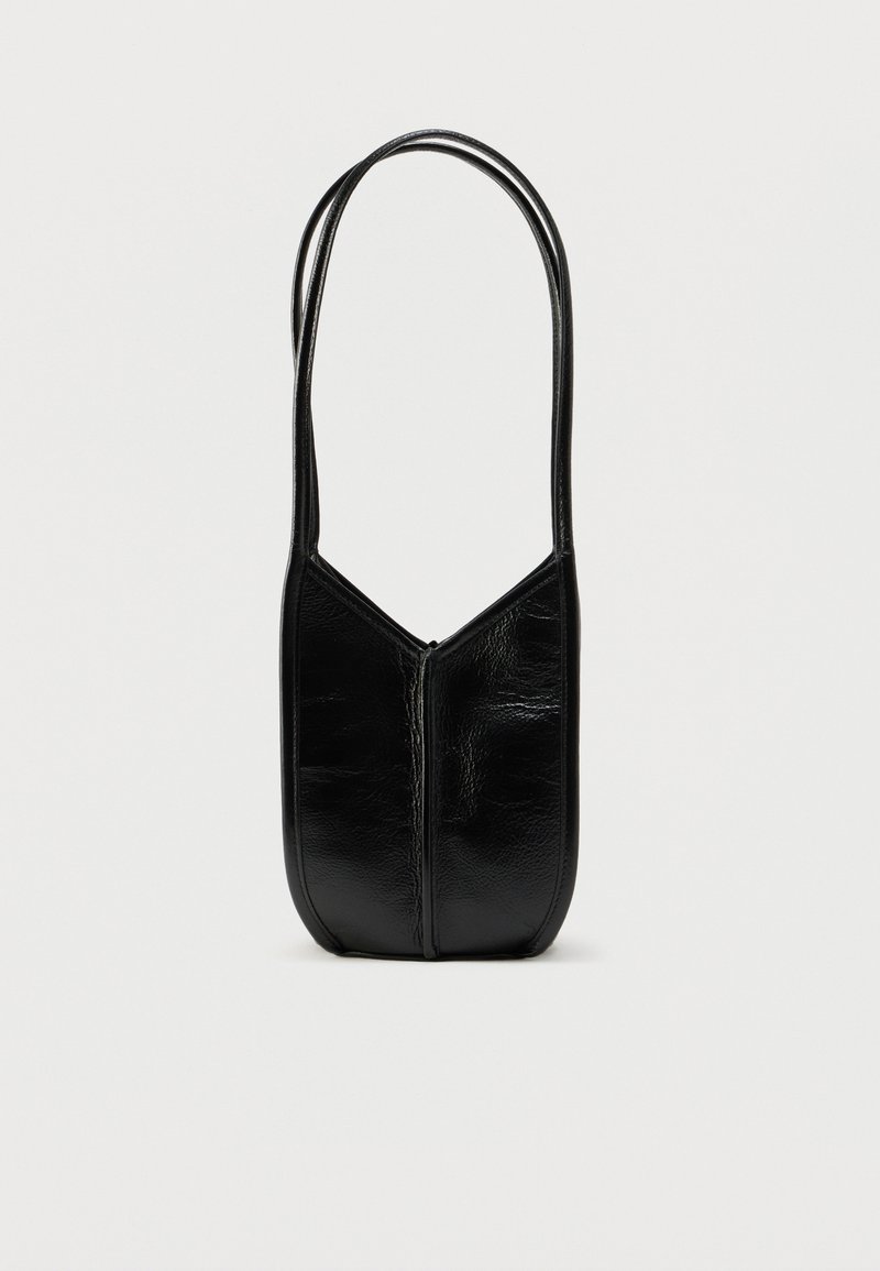 Μαύρη δερμάτινη τσάντα με στρογγυλεμένο, ασύμμετρο σχήμα. Διαθέτει δύο μακριές λουράκια και μια αδιάκοπη φερμουάρ κατά μήκος του μπροστινού μέρους. Λείο υφή.