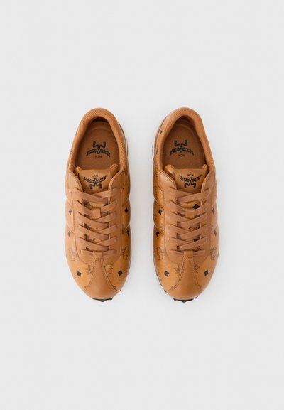 Καφέ δερμάτινα αθλητικά παπούτσια με κούμπωμα με κορδόνια μπροστά, μαύρες λεπτομέρειες και ανάγλυφα λογότυπα. Διαθέτουν διακοσμητικά μοτίβα ρόμβου στις πλευρές και σόλες με υφή για καλύτερη πρόσφυση.