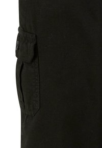 Poche cargo en tissu noir avec rabat et fermeture par bouton, montrant des coutures détaillées et un matériau texturé.