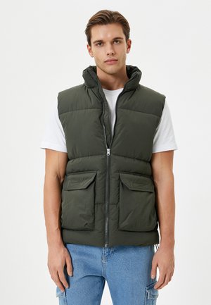 Mørkegrøn puffer vest med hætte, frontlynlås og to brystlommer. Tekstureret materiale med en glat overflade og en afslappet pasform.