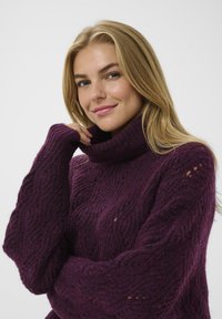 Sweter z golfem, dziany, w głębokim purpurowym kolorze, z teksturowanym wzorem i ściągaczami na mankietach, o luźnym kroju i długich rękawach.