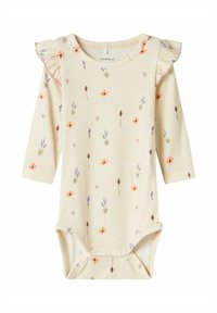 Cremfarbener, gerippter Baby-Body mit langen Ärmeln, floralem Muster, Rüschendetails an den Schultern, Druckknopfverschluss am Boden und weicher Textur.