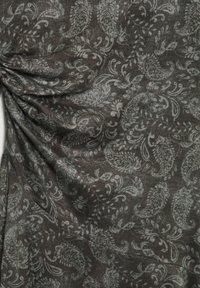 Tissu foncé avec un motif paisley gris clair complexe présentant des motifs de feuilles et de fleurs tourbillonnants, montré avec de douces plis et une texture.