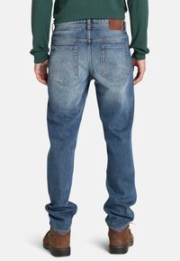 Blaue Denim-Jeans mit einem lockeren Schnitt, zwei Gesäßtaschen, einem Lederpatch am Bund und dezenten Verblassungen entlang der Beine.