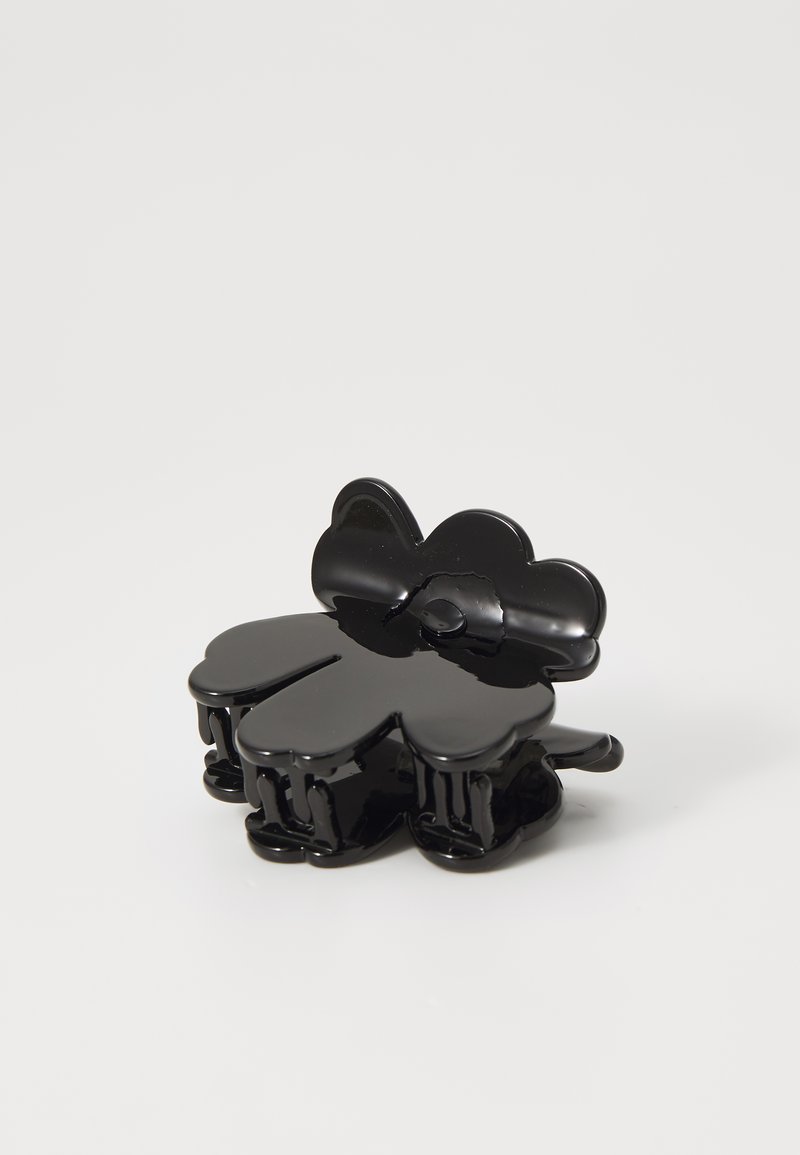 Μαύρη τσιμπίδα μαλλιών σε σχήμα λουλουδιού, κατασκευασμένη από γυαλιστερό πλαστικό, με τέσσερα στρογγυλά πέταλα και κεντρικό κούμπωμα για ασφαλή στήριξη.