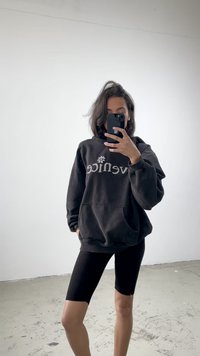Sweatshirt preto com o texto "venice" e gráfico de flor, combinado com calções de ciclismo pretos. Tecido suave e corte casual, exibido num espelho.
