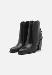 Schwarze Leder-Ankle Boots mit spitzem Zeh, einem hohen Blockabsatz und einem Reißverschluss auf der Rückseite für einfaches An- und Ausziehen. Glatte Textur und elegantes Design.