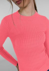 Rippstrick-Pullover mit langen Ärmeln in leuchtendem Pink. Mit rundem Halsausschnitt und strukturiertem Finish, das das figurbetonte Design betont.