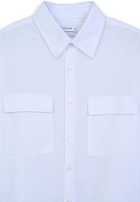 Camicia bianca con bottoni realizzata in tessuto leggero. Presenta un colletto a punta, due tasche sul petto e bottoni simili a perle.