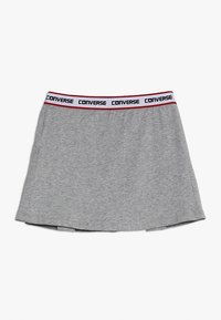 Šedá bavlněná sukně s širokým elastickým pasem, na kterém je černý nápis "CONVERSE" a červený akcent. Jednoduchý A-liniový tvar, hladká textura.