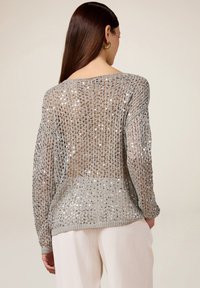Zilveren pailletten trui met een losgebreid ontwerp, voorzien van lange mouwen en een brede halslijn. Textuur, lichtgewicht materiaal.